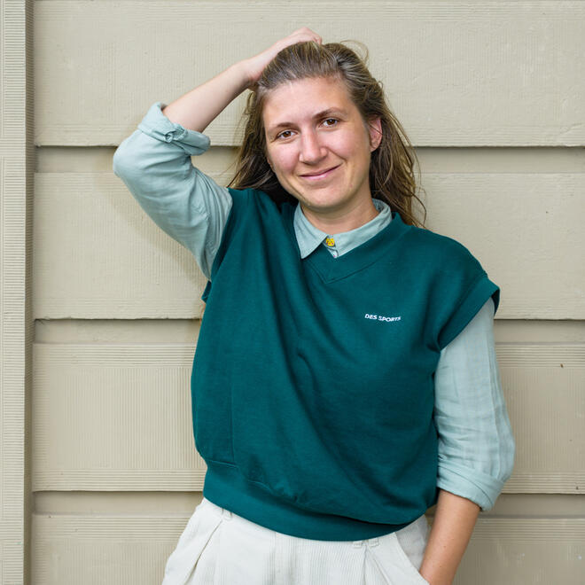 Foto van Jozien Wijkhuis, een jonge vrouw met lang bruin haar, een rode trui een een zwarte broek aan.