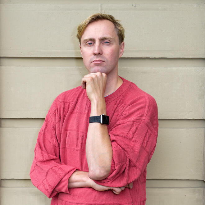 Foto van Lieven Heeremans, hij springt in de lucht over een paaltje heen. Hij is blond en draagt een gele trui en een blauwe broek